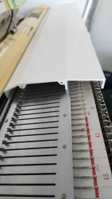 Magnetic bed cover lifted to show the needles of a Brother bulky machine